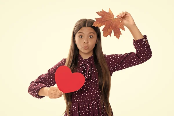 funny child having fun with maple leaf isolated on white background. autumn love. childhood happiness. natural beauty. fall season fashion. teen girl hold heart. valentines day. be my valentine.