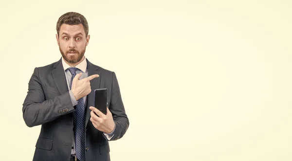 Business professional man in formal suit hold mobile phone pointing finger for copy space isolated on white, advertising.