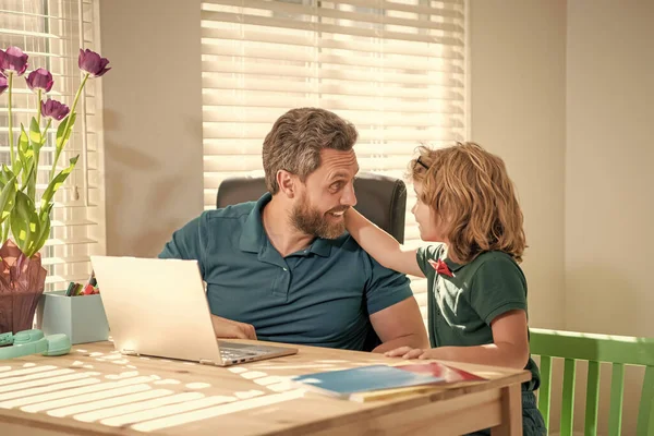 bearded dad or school private tutor teaching boy son with modern laptop, family.