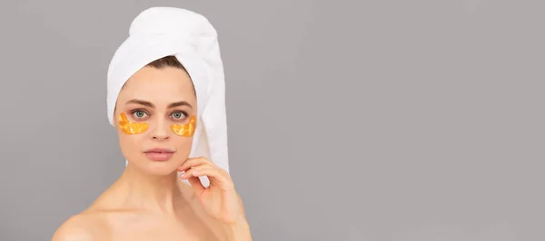 Eye patches, patch under eyes. sensual lady with terry towel use facial golden eye patch for skin, hydrogel. Beautiful woman isolated face portrait, banner with mock up copy space