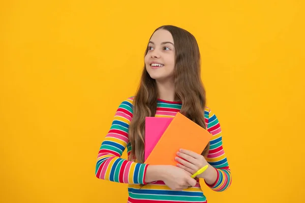 Schoolgirl with copy book posing on isolated background. Literature lesson, grammar school. Intellectual child reader