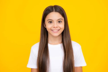 Happy teenager portrait. Portrait of cute positive little girl isolated on yellow background. Attractive caucasian child smiling and looking at camera. Smiling girl