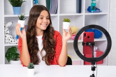 Genç çocuk akıllı telefonuyla sosyal medya için video dersi kaydediyor. Nüfuzlu genç, çevrimiçi yayınlanırken blog için yeni içerik oluşturuyor. Mutlu kız yüzü, pozitif ve gülümsüyor.