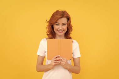 Sarı arka planda mutlu bir öğrenci. Kız kitapla çalışıyor. Özel öğretmen planlamacı. Kitap aşığı. Okula dönüyorum. Eğitim ve bilgi. Kadın okuyucu.