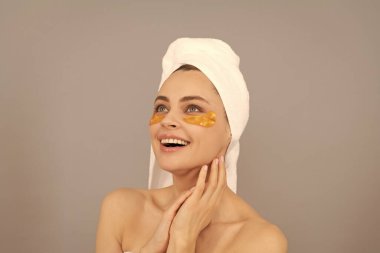 Havlusu olan mutlu bir kız cilt için altın göz bandı kullanır..