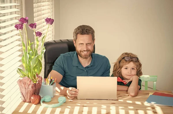 bearded dad or school private tutor teaching boy son with modern laptop, education.