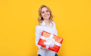 woman smile with big present box on yellow background.