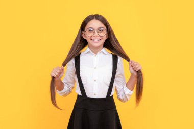 cheerful kid hold long hair in school uniform and glasses for vision protection, hair.