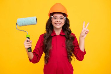 Renovation for childrens room. Little girl in protective helmet and paint brush for painting walls. Happy face, positive and smiling emotions of teenager girl