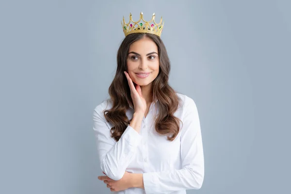 Pretty young woman wear crown, isolated on gray background. Girl with golden crown, arrogance and privileged status, concept of success and dreams