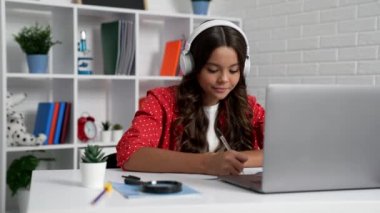 teen girl in headset writing while online education, lesson.