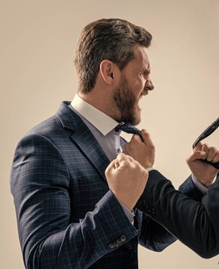 Takım elbiseli saldırgan adam çığlık atıyor. Meslektaşı gri arka planda yumruk yumruğa kavga ediyor. Fiziksel saldırı..