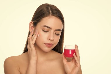 Beyaz arka planda izole edilmiş cilt kremi süren genç bir kız, günlük alışkanlık..