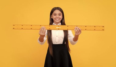 Gülümseyen genç kız cetvel tutuyor. Okula dönüyorum. Cebir ve geometri. Çocuk matematik okuyor. Boyutunu ölçün. Trigonometri kırtasiyesi. Ölçme ve ölçme. Çocuk eğitimi. Matematik.