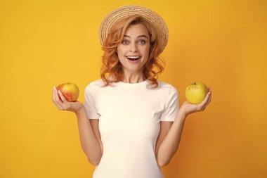 Sağlıklı dişleri olan gülümseyen kızıl saçlı kadın elma tutuyor. Stüdyoda izole edilmiş