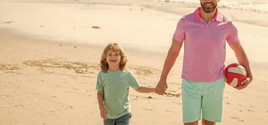 kid and cropped dad walking on beach in summer vacation holding ball, family.