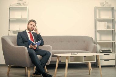 Takım elbiseli olgun bir iş adamının planlamacıyla ofiste oturduğunu düşünüyor..