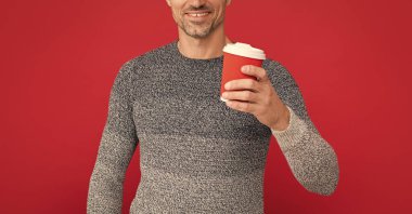 Kahve içen ağarmış bir adam. Erkek manken bardağı. Kış modası. Sabah kahvesi. Kırmızı arka planda gri kazaklı mutlu adam..