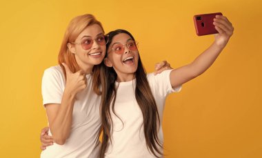 Şık anne ve çocuk blogcuları. Mutlu kadın ve kız akıllı telefonla selfie çekiyorlar. Selfie ailesi. Modern hayat. mobil teknoloji. Görüntülü arama yapıyorum. Anne-kız vloglama. çevrimiçi iletişim.