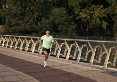 Spor kıyafetleri içinde koşan atletik bir adam..