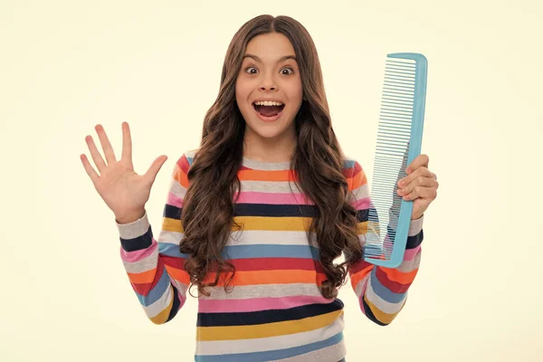 Teenage girl with brush combing hair. Girl taking hairstyle. Child brushing hair with comb, kids haircare. Excited face, cheerful emotions of teenager girl