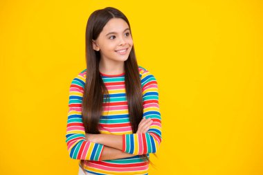 Teenage girl kid with crossed arms, looking at camera, isolated on yellow studio background. Happy face, positive and smiling emotions of teenager girl
