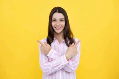 Woman point at copy space, showing copyspace pointing. Promo, girl showing advertisement content gesture, pointing with hand recommend product. Isolated yellow background
