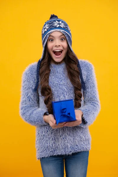 Funny kid girl in winter wear holding gift boxes celebrating happy New Year or Christmas. Winter holiday. Excited face, cheerful emotions of teenager girl