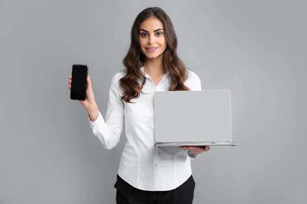 Happy girl using mobile phone and laptop. Woman showing empty laptop screen, mock up template with copy space