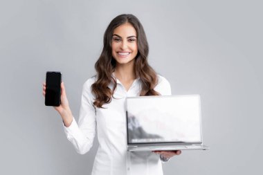 Smiling girl using mobile phone and laptop. Woman showing empty laptop screen, mock up template with copy space