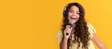 child singer sing karaoke in microphone. online vocal education. Child portrait with headphones, horizontal poster. Girl listening to music, banner with copy space