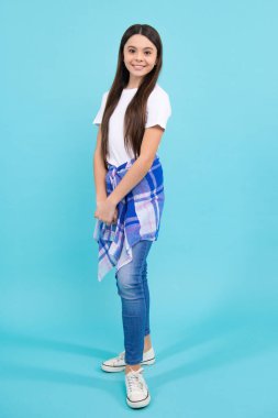 Full length of attractive cheerful teenager child girl in casual fashion clothes over blue isolated background. Happy teenager, positive and smiling emotions of teen girl
