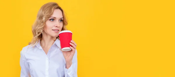 blonde woman with coffee cup and smartphone on yellow background. Woman isolated face portrait, banner with mock up copy space