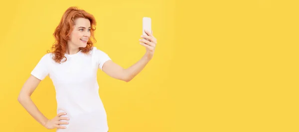 Happy girl smile to mobile camera phone yellow background, video selfie. Woman isolated face portrait, banner with mock up copy space