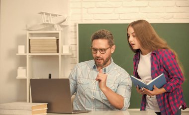 Yoğun öğrenci ve dizüstü bilgisayarı olan özel öğretmen. Baba ve genç kız ders çalışıyor. Özel öğretmen ve çocuk defterini tutuyor. Aile yardımı. Baba ve kızı defter kullanıyor. Okula dönüyorum. çocukluk eğitimi.