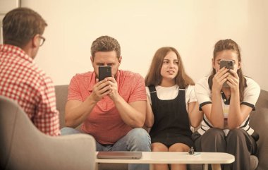 Baba ve kız psikolog seansında. Aile terapisi. Çocuklu aileler sosyal hizmetlilerle konuşur. Telefon bağımlısı anne, baba ve kız. Hayat sigortası ve evlat edinme. veli toplantısı.