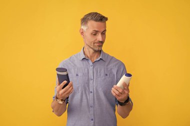 Erkek sarı arka planda şampuanı, saç bakımını seçer..