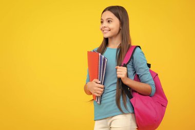 Okula dönelim. Ergen liseli kız kitaplarını ve kitaplarını öğrenmeye hazır tutuyor. İzole edilmiş sarı stüdyo geçmişi olan okul çocukları. Mutlu ergen portresi. Gülümseyen kız