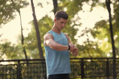 Aktif giyimde erkek koşucu Akıllı Saati kontrol ediyor.