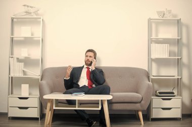 İş adamı ofisinde oturuyor ve telefonda konuşuyor..