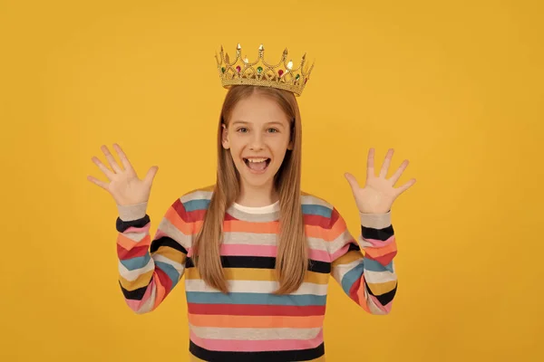glad teen child in queen crown on yellow background.