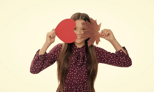 teen girl hold heart. valentines day. be my valentine. happy child having fun with maple leaf isolated on white background. autumn love. childhood happiness. natural beauty. fall season fashion.