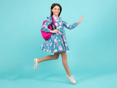 Okul üniformalı, sırt çantalı bir kız. Mavi soyutlanmış genç bir kız öğrenci. Öğrenme ve eğitim çocukları. Koş ve atla. Mutlu ergen, pozitif ve gülümseyen duygular