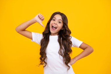Onun yakın plan portresi. Güzel, çekici, neşeli, şaşkın kız, sarı arka planda izole edilmiş fotokopi alanını işaret ediyor. Şaşırmış genç kız. Heyecanlı bir ifade, neşeli ve mutlu.