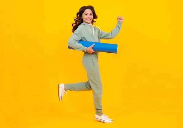 Teenage girl dressed in sports uniform, posing in the studio. Child in a posh stylish sports suit in a hoodie with a hood. Advertising sportswear and yoga wear. Healthy kids lifestyle, sport