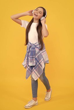 Kulaklıklı mutlu çocuk sarı arka planda şarkı söylemekten hoşlanıyor, müzik.