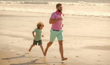 Baba ve çocuk dışarıda eğleniyorlar. Çocukluk ve ebeveynlik. Baba ve oğul yaz plajında koşuyor. Aile seyahati ve tatil. Babalar ya da aile günü. Baba ve çocuk yaz günü.