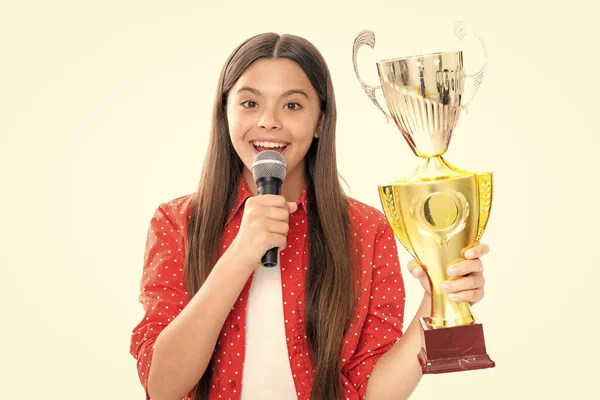 Girl with win cup microphone speech. Teen holding a trophy. Kid winner child won the competition, celebrating success and victory. Portrait of happy smiling teenage child girl