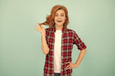 Mavi arka planda kareli gömlekli kızıl saçlı kız şaşırdı..