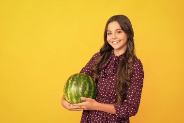 Sarı arka planda karpuz. Meyveli çocuk. Çocuklar için sağlıklı yiyecekler. Yaz tatilinde früktoz sağlıklı beslenme. Genç kız eğleniyor. Yaz zamanı. Neşeli çocuk kavunu tut.